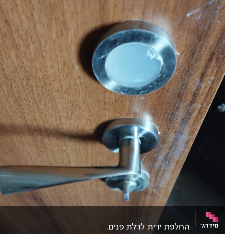 ידית דלת מתכתית על דלת עץ חומה